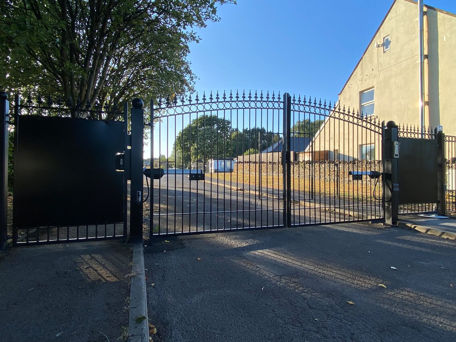 Black steel gates and matching railings with spear top finials at a roadside entrance